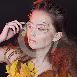 Young woman with autumn make up and leaves on head and her body