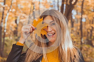 Young woman with autumn orange maple leaf over fall season background