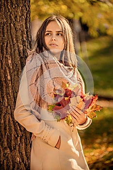 young woman in autumn park with bouquet of bright autumn leaves