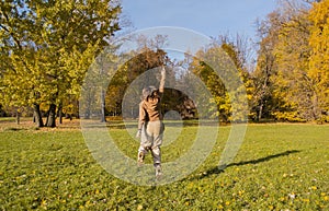 A young woman in an autumn park enjoys freedom. She jumps with arms up like superhero Wonder Woman