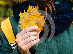 Young woman in autumn park with faded leaves in hand. Autumn mood. Selective focus