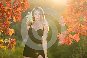 Young woman in autumn park. Warm sunny weather. Fall concept. Hello autumn. Happy woman with autumn yellow leaves