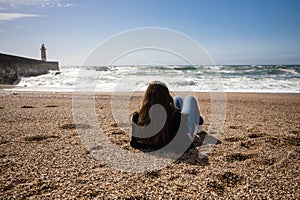 Young woman is enjoying the beach on the Praia de Carnero, beach in Porto with big waves of the ocean photo
