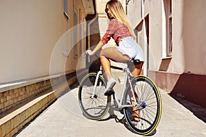 Young woman back on sport fixed gear bicycle posing on outd