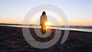 A young woman on the background of the sunset the sun on the seashore does exercises exercised by running, stretching and slumping