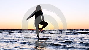 A young woman on the background of the sunset the sun on the seashore does exercises exercised by running, stretching and slumping