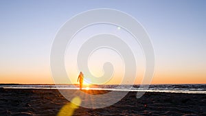 A young woman on the background of the sunset the sun on the seashore does exercises exercised by running, stretching and slumping