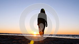 A young woman on the background of the sunset the sun on the seashore does exercises exercised by running, stretching and slumping