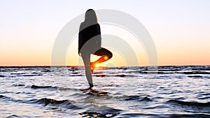 A young woman on the background of the sunset the sun on the seashore does exercises exercised by running, stretching and slumping