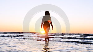 A young woman on the background of the sunset the sun on the seashore does exercises exercised by running, stretching and slumping