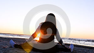 A young woman on the background of the sunset the sun on the seashore does exercises exercised by running, stretching and slumping