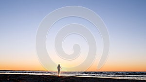 A young woman on the background of the sunset the sun on the seashore does exercises exercised by running, stretching and slumping