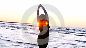 A young woman on the background of the sunset the sun on the seashore does exercises exercised by running, stretching and slumping