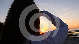 A young woman on the background of the sunset the sun on the seashore does exercises exercised by running, stretching and slumping