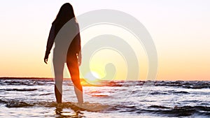 A young woman on the background of the sunset the sun on the seashore does exercises exercised by running, stretching and slumping