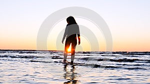 A young woman on the background of the sunset the sun on the seashore does exercises exercised by running, stretching and slumping