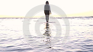 A young woman on the background of the sunset the sun on the seashore does exercises exercised by running, stretching and slumping