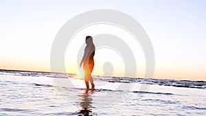 A young woman on the background of the sunset the sun on the seashore does exercises exercised by running, stretching and slumping