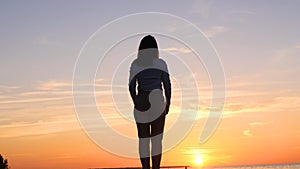 A young woman on the background of the sunset the sun on the seashore does exercises exercised by running, stretching and slumping