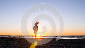 A young woman on the background of the sunset the sun on the seashore does exercises exercised by running, stretching and slumping