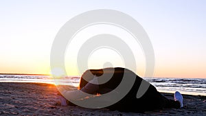 A young woman on the background of the sunset the sun on the seashore does exercises exercised by running, stretching and slumping