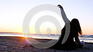 A young woman on the background of the sunset the sun on the seashore does exercises exercised by running, stretching and slumping