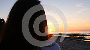 A young woman on the background of the sunset the sun on the seashore does exercises exercised by running, stretching and slumping