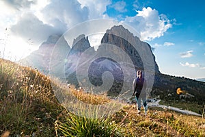 Young woman in backlight watching sunset on mountain rock towers of Langkofel Group, Grohmannspitze mountain, Fuenffingerspitze