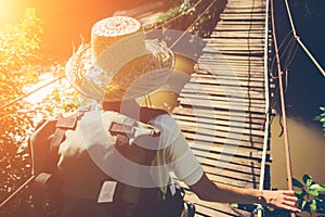 Young woman with backpack and hat traveling across danger hanging bridge