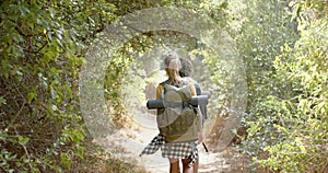 A young woman with a backpack hikes through a lush forest