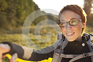 Young woman with backpack in a meadow showing way . Hiking at summertime.