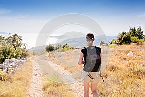 Young woman with backpack at mountain trail.