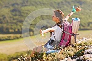 Young woman with backpack sitting on cliff's edge