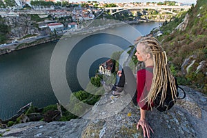 Young woman with backpack sitting on cliff`s edge and looking at the river. Travel.