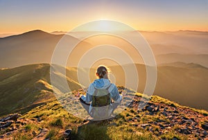 Young woman with backpack sitting on the mountain peak