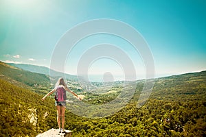 Young woman with backpack standing on cliff edge