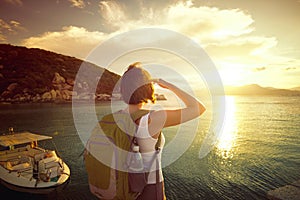 Young woman with backpack standing on the pierce and admiring by