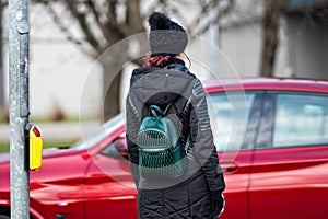 Young woman with backpack waiting to cross street, traffic rules and regulations