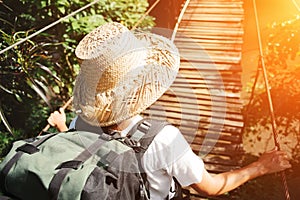 Young woman with backpack walking across hanging bridge