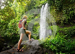 Young woman backpacker looking at the waterfall in jungles.