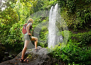 Young woman backpacker looking at the waterfall in jungles. photo