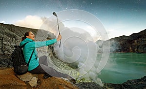 Young woman with backpacker taking selfie on top volcano