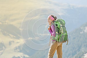 Woman backpacker tourist standing on a top of the mountain ridge