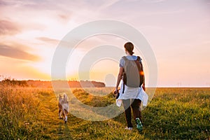 Young Woman Backpacker Walking With Dog In Summer Meadow Grass D