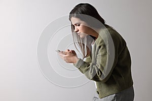 Young woman with bad posture using smartphone on background. Space for text