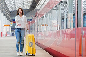Young woman with baggage at a train station. Caucasian tourist waiting her express train