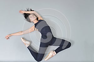 Young woman ballerina lying and stretching on the floor at ballet studio, view from above.