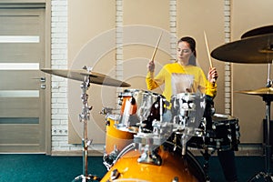 Young woman banging on a drum kit. Playing musical instruments.