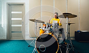 Young woman banging on drums.