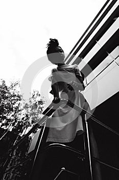 Young woman with bare legs dressed in white sneakers and a long T-shirt, against the backdrop of cityscapes